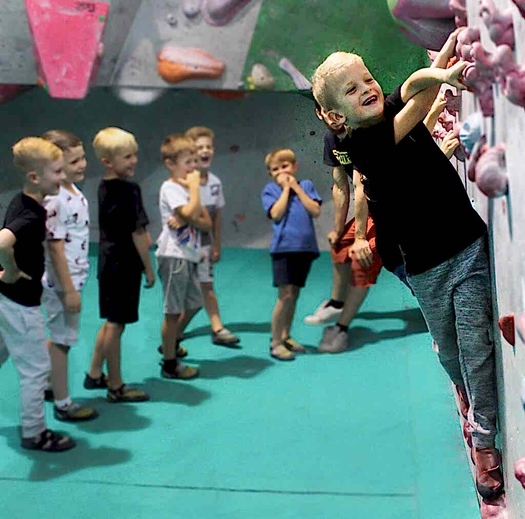 children watching a boy climb at city bloc